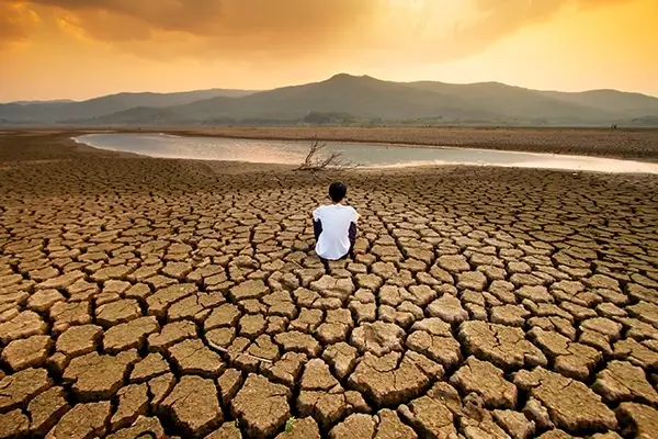 person sitting in desert with a body of water in the background