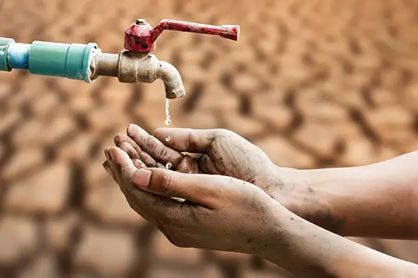 hands collecting water from a tap in the desert